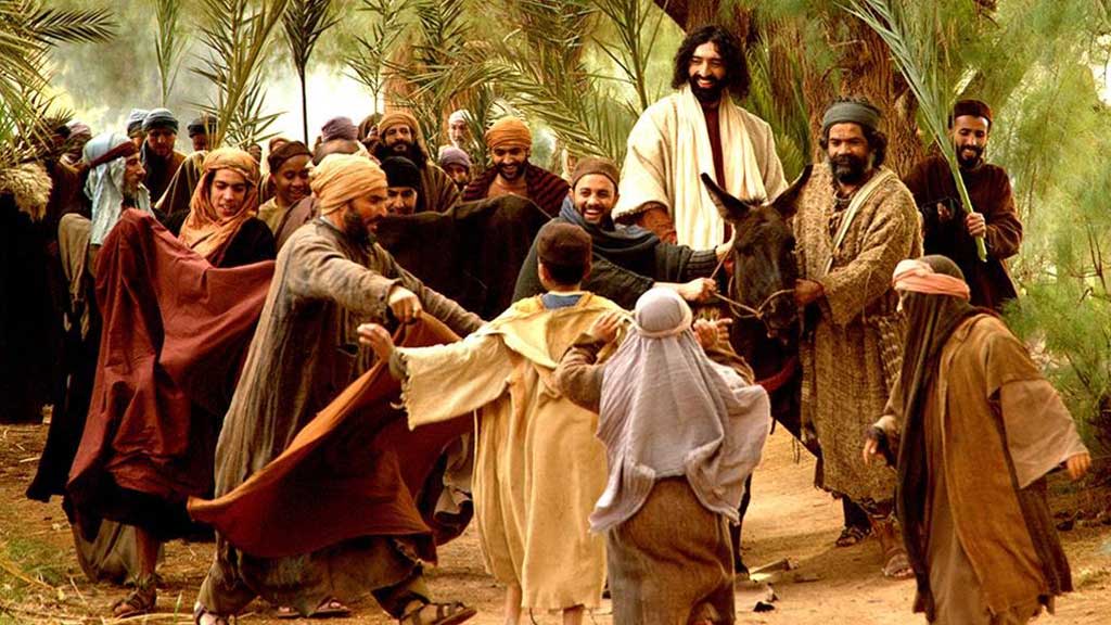 Jeesus ratsastaa aasilla Jerusalemiin
